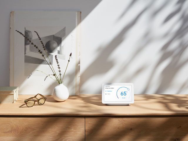 Google Home Hub on sideboard with a pari of glasses and vase of lavender