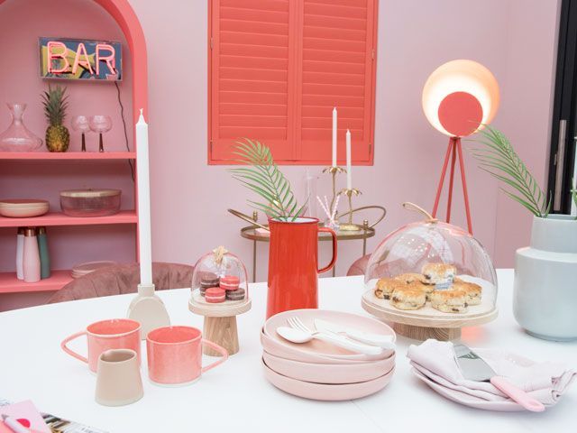 living coral dining area with deep coral shutters and statement lighting at the good homes roomsets at Ideal Home Show 2019