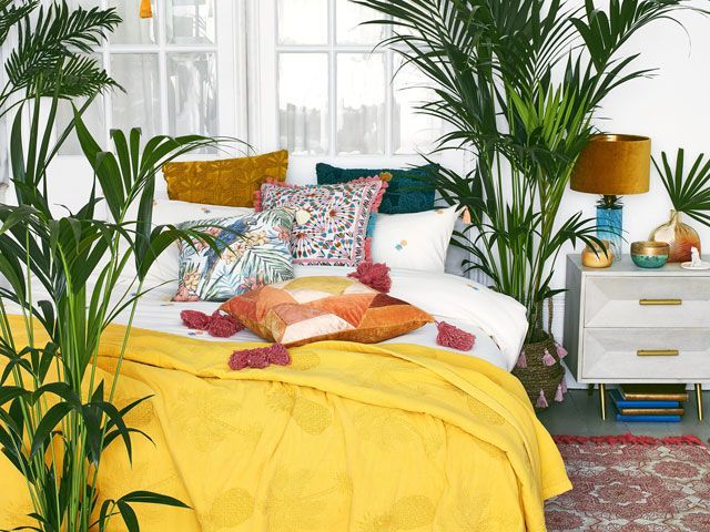 maximalism: a selection of cushions on a bed in a bright bedroom focussing on the maximalism trend from Debenhams Matthew Williamson ss19 collection