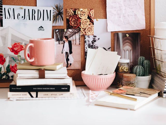 a photo of a desk with a pink cup, style books and notebooks by ella jardim