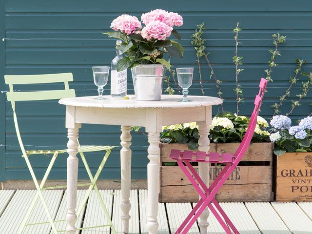 pink chair and lime green painted chair by a vintage style coffee table with plants in crate planters by Valspar