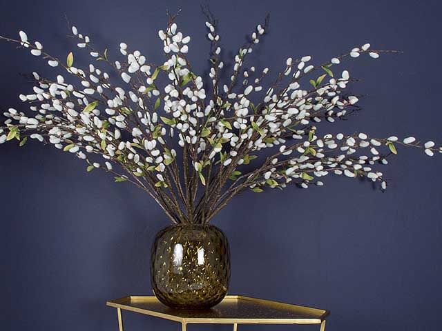 pussy willow in round vase in front of dark blue wall - best artificial flowers - Audenza - goodhomesmagazine.com