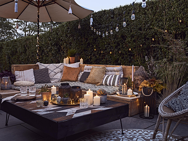 garden party essentials: outdoor lounge set up with cushions, candles and blankets
