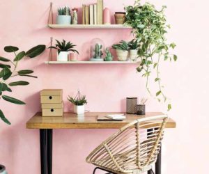 Stylish workspace home office with pastel pink wall, rustic shelves and desk, rattan desk chair and plants - goodhomesmagazine.com