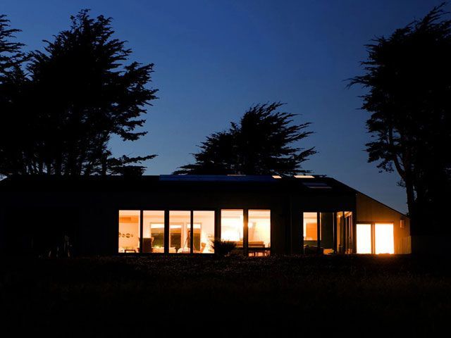 a house at night in the dark surrounded by trees with lights on inside