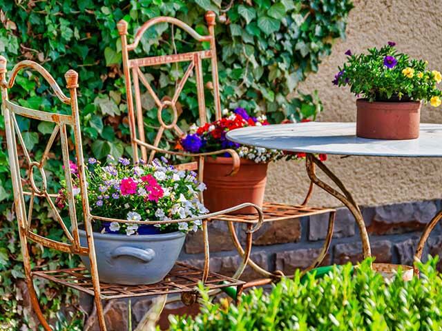 bright flowers in pots around garden table - keep wasps away - goodhomesmagazine.com