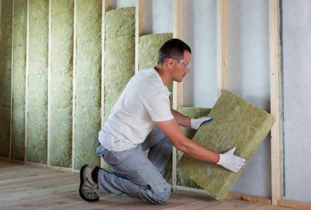 A man installing stone wool wall insulation