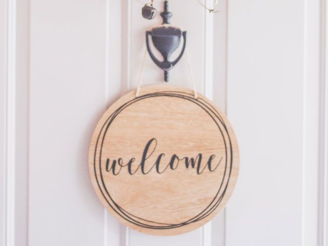 welcome sign on a white door with black knocker