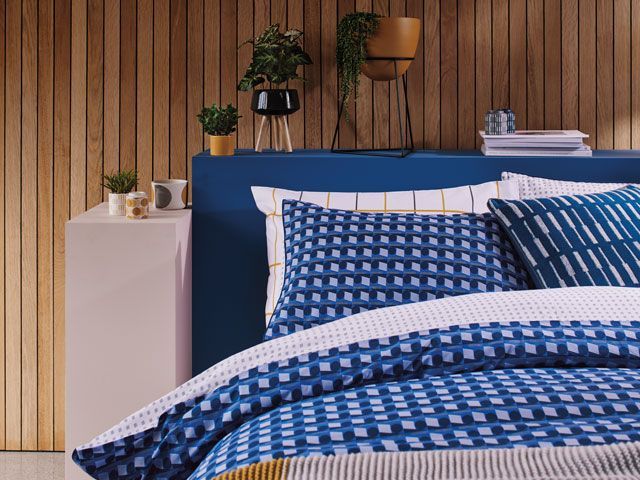 blue checked bedding in a wood clad bedroom with plants in stylish planters by Sainsbury's Home