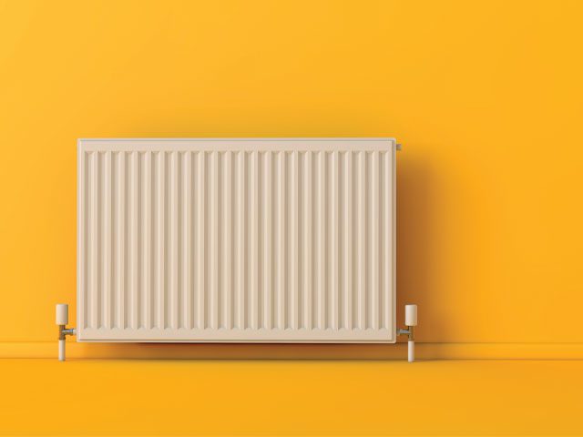 Radiator against a yellow wall by ink drop/adobe
