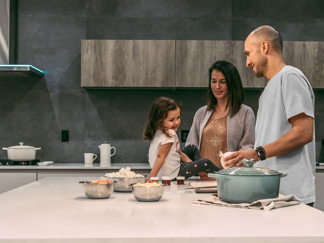 young family cooking in a modern kitchen with grey-tiled walls