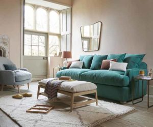 Teal sofa bed with scattered cushions and gootstool with fluffy cream rug, goodhomesmagazine.com