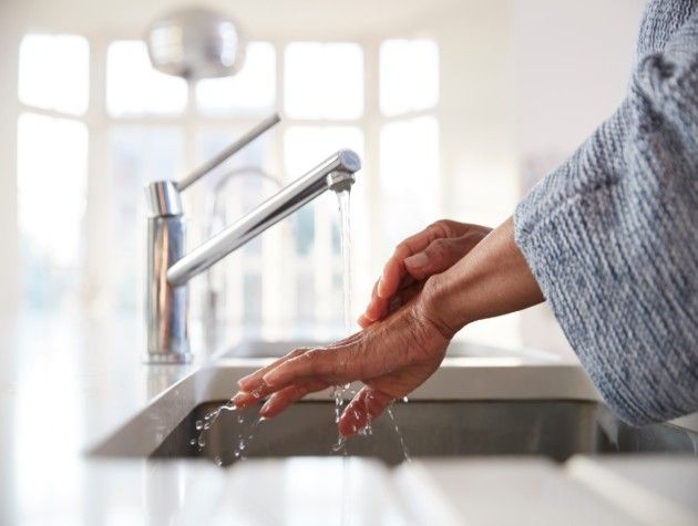 Woman washing hands under running tap