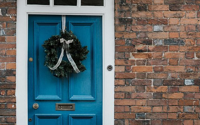 blue front door with christmas wreath annie spratt for unsplash - news - goodhomesmagazine.com