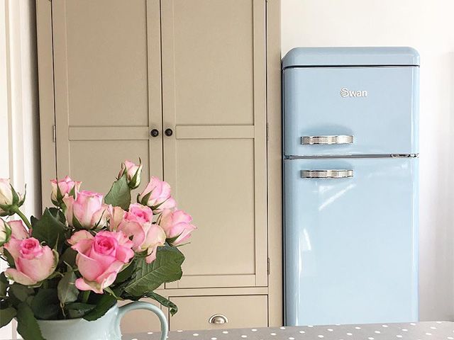 swan retro fridge freezer next to a neutral cupboard with flowers on counter