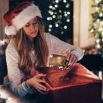 Woman in Christmas hat unwrapping present - Credit: Roberto Nickson