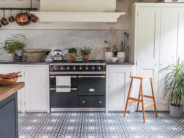 traditional black oven set up with black and white tiled floor and rustic saucepans, goodhomesmagazine.com