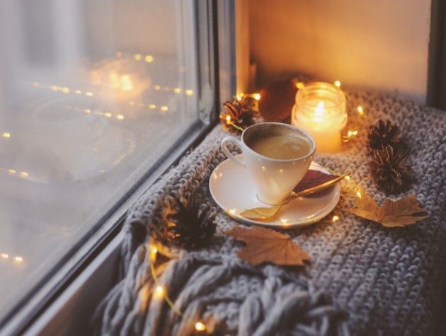 A candle next to a cup of hot chocolate