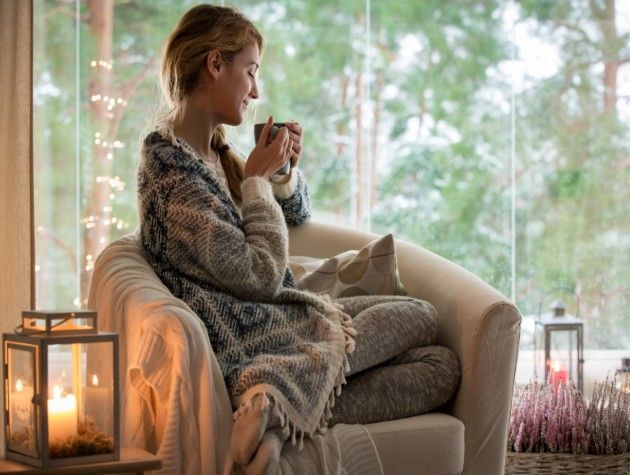 A woman enjoying a hot drink next to a candle