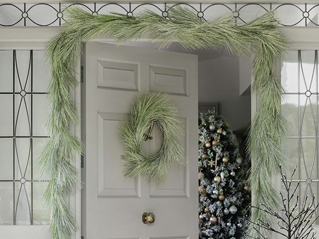 amara frosted pine wreath and garland on christmas front door - goodhomesmagazine.com