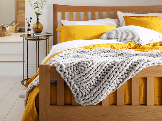 Bed with yellow sheets and grey throw - pantone colour of the year 2021 - goodhomesmagazine.com