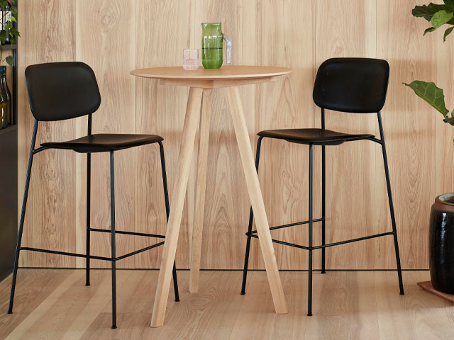 black bar stools with back rest in a room with wooden floors, wooden wall panelling and wooden table