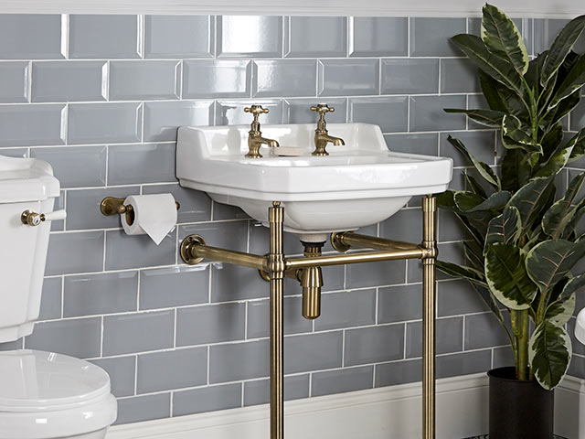 grey tiled walls with white basin with brass taps and plugs