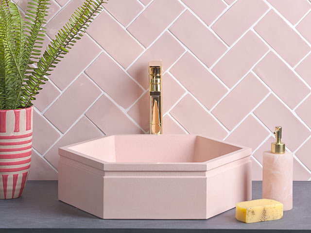 pink hexagon basin in pink tiled bathroom with gold taps