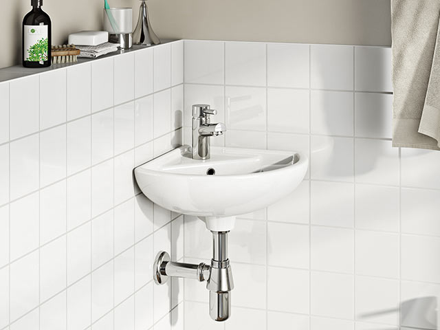 White corner basin over white tiles with silver taps