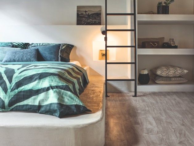 bedroom with mattress on plinth shelves and ladder