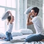 father and daughter having pillow fight on bed