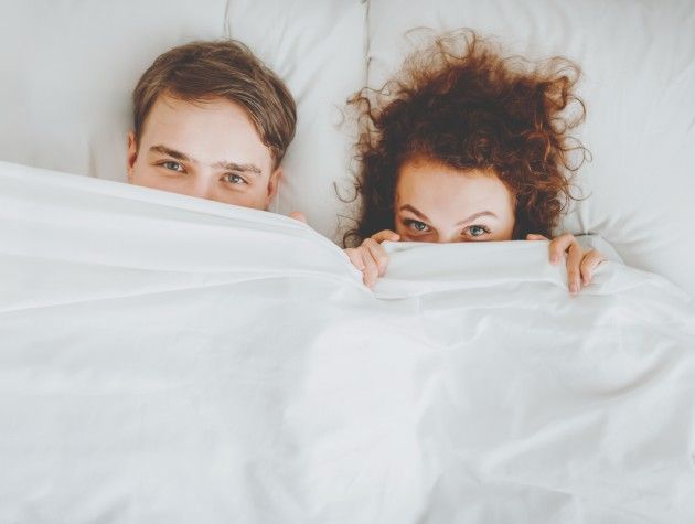 man and woman peeking out from behind duvet copy