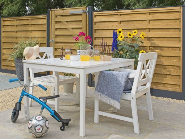 table chairs and childrens toys in back garden with wooden fencing