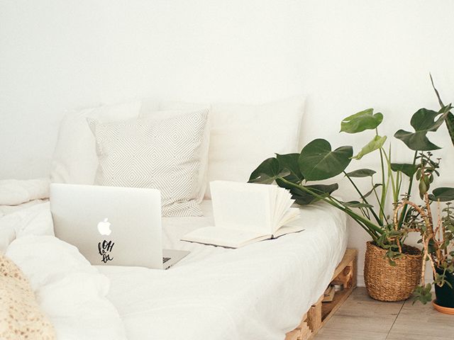 turned on silver macbook on white bed - bedroom - goodhomesmagazine.com