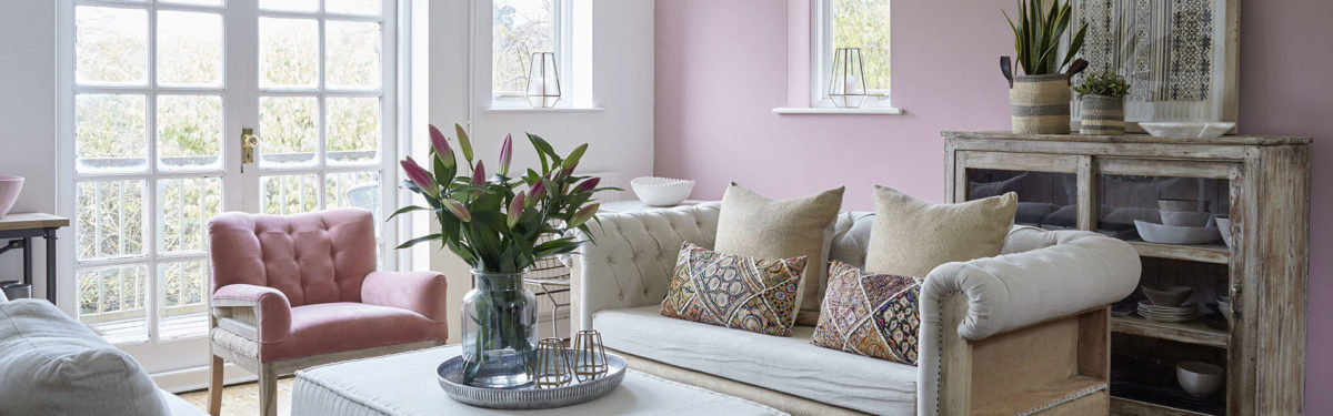 Buttoned sofa and armchair with cut lilies in pink living room, Tunbridge Wells home, Kent, UK. Image: Brent Darby/Narratives