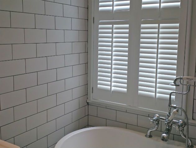 bathroom with tiled wall bath and shutters