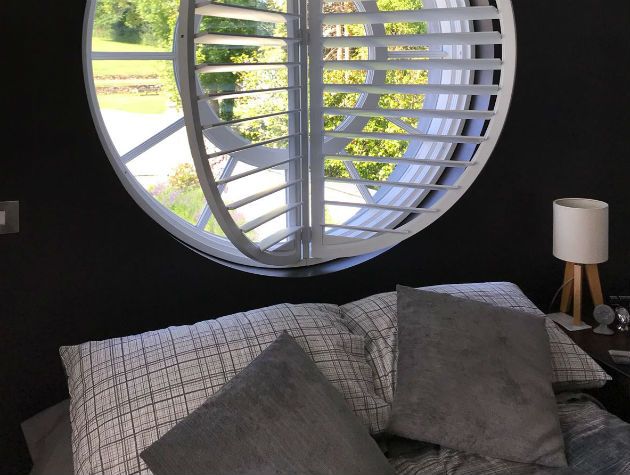 bedroom with round window and circular shutters