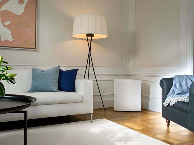 blueair air purifier in white living room with a rug and a floor lamp