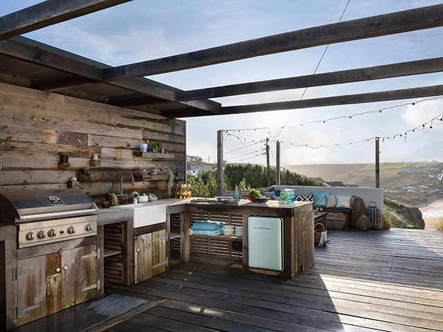 alfresco kitchen on an expansive terrace in cornwall with views of the beach in the background