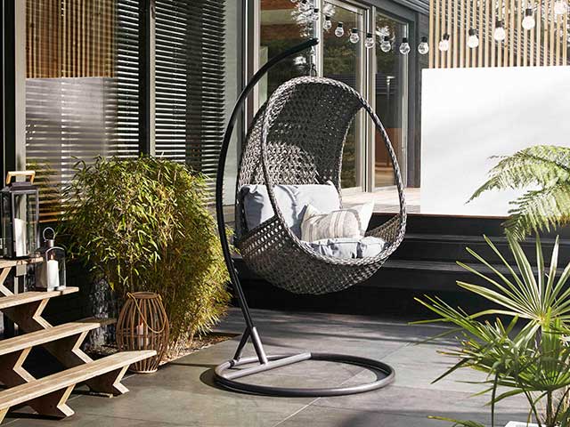 Camber hanging egg chairs in courtyard setting with plants surrounding