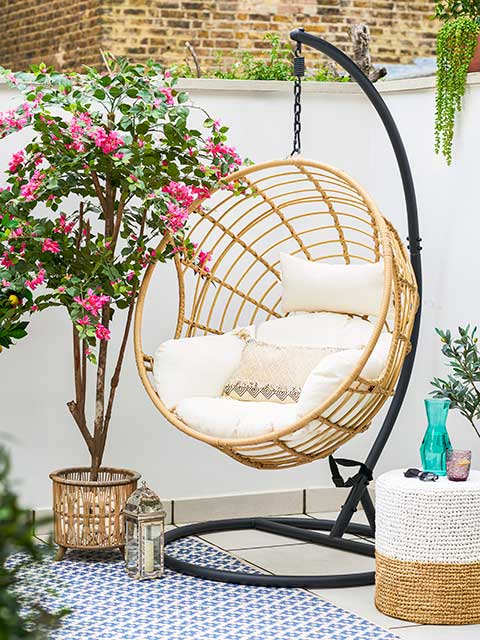 Hanging egg chairs in garden next to pink flowering plant