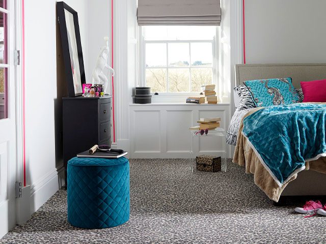 Animal print carpet in a bedroom with teal bedding and footstool