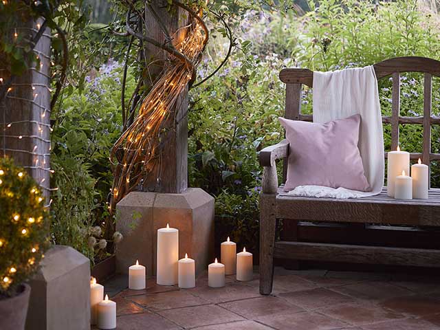Fairy garden with wooden benches, electric candles and dairy lights around wooden beams