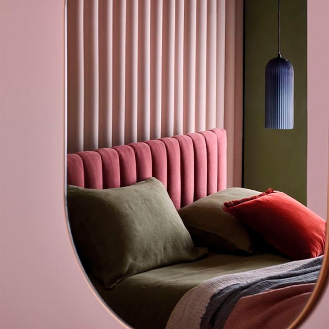 pink scalloped headboard with pink scalloped panelling reflected in a mirror