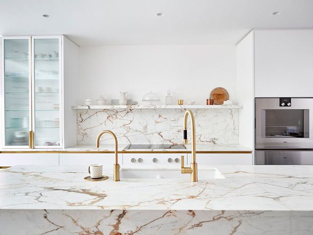 White kitchen with statement stone surfaces and brass detailing - goodhomesmagazine.com