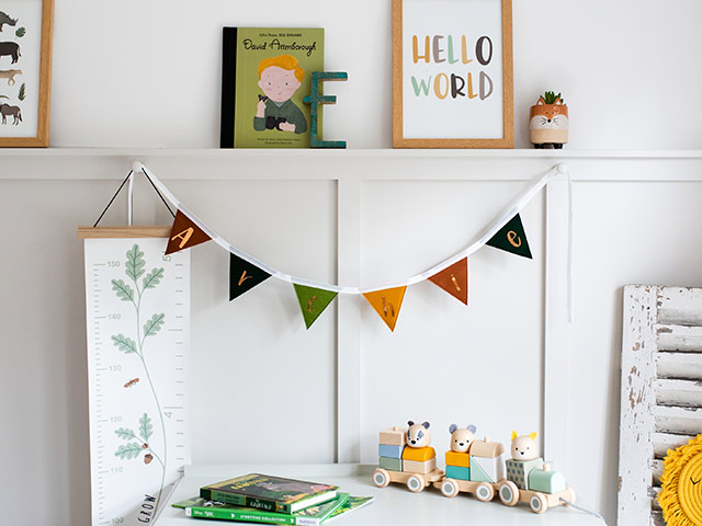 Gender neutral nursery colourful bunting and toys in white panelled room