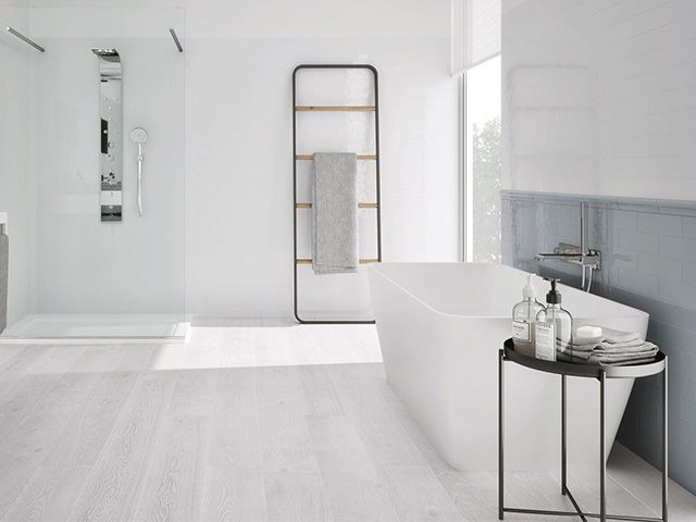 black storage ladder in a white bathroom with pale wooden flooring and grey panelled wall