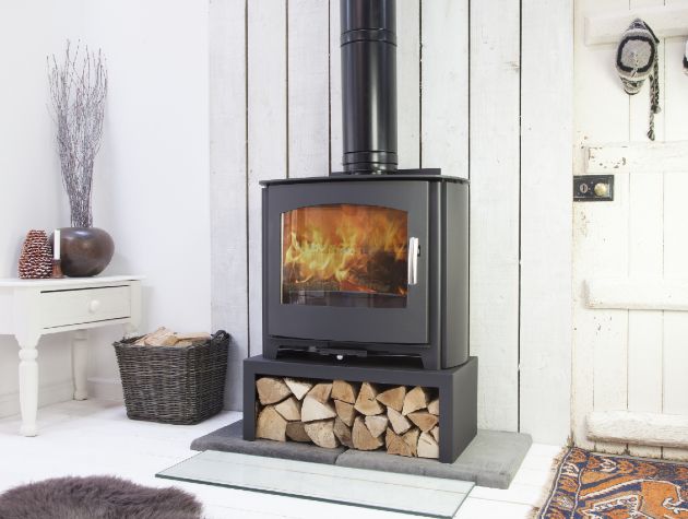 black stove with flames in white room with log store