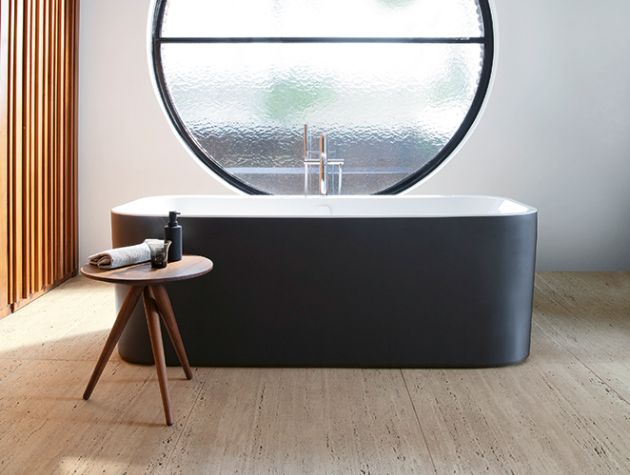freestanding black bath in front of circular window