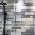 shower and sink with black and grey tiles
